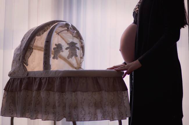 pregnant-woman-standing-near-white-brown-bassinet